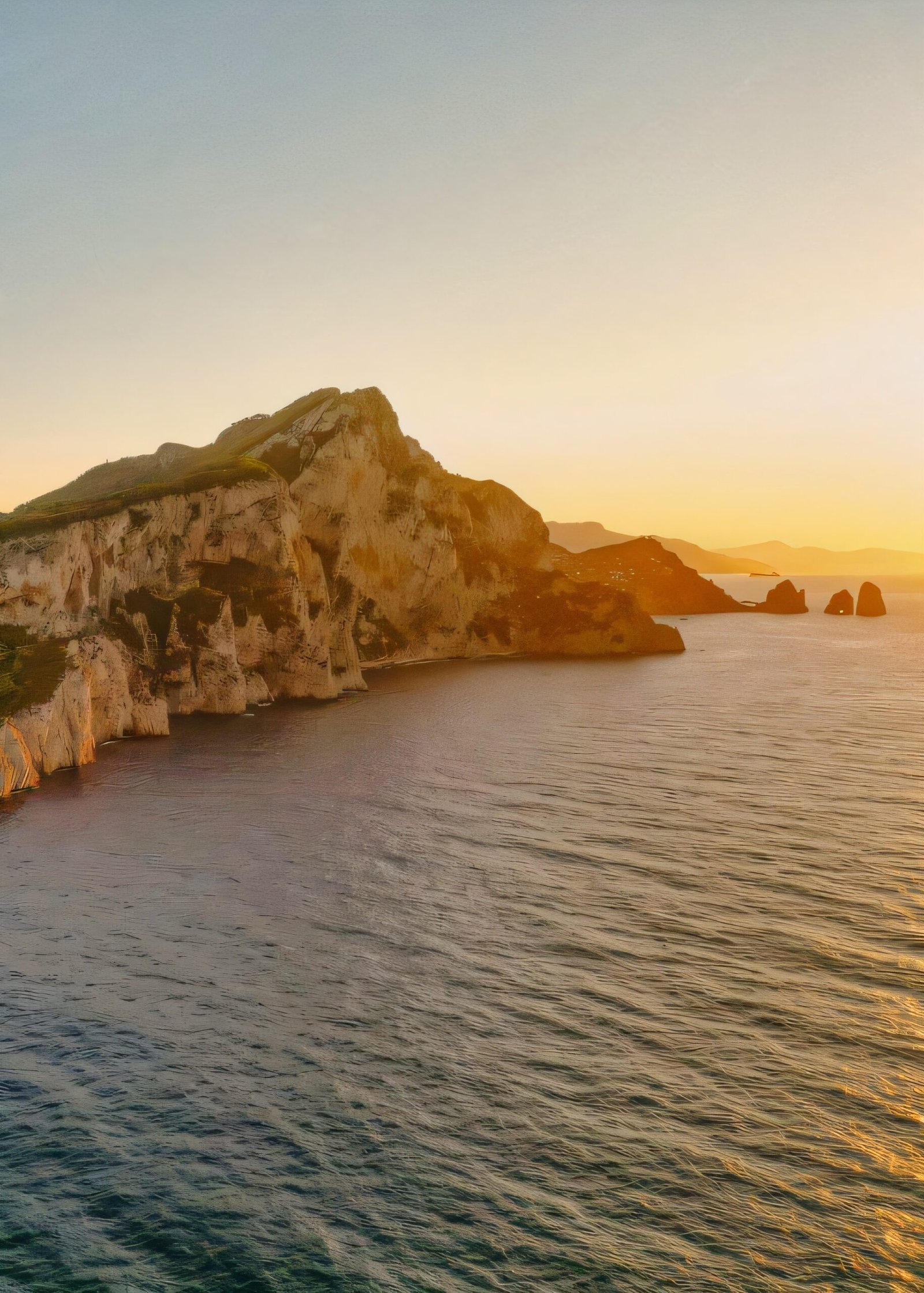 Golden hour light across Capri's rocky coastline and distant sea stacks