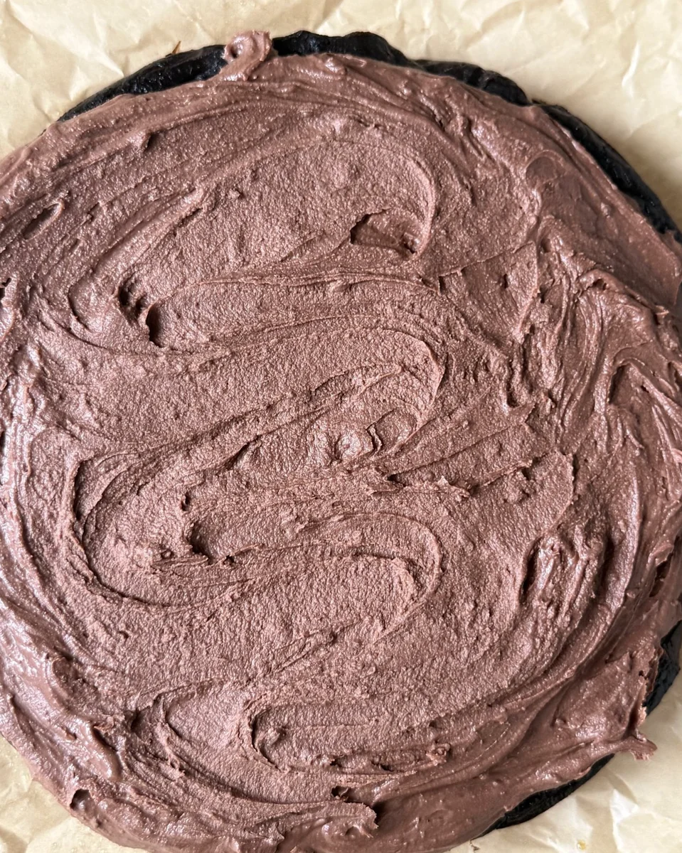 Silky chocolate ganache frosting being stirred in bowl