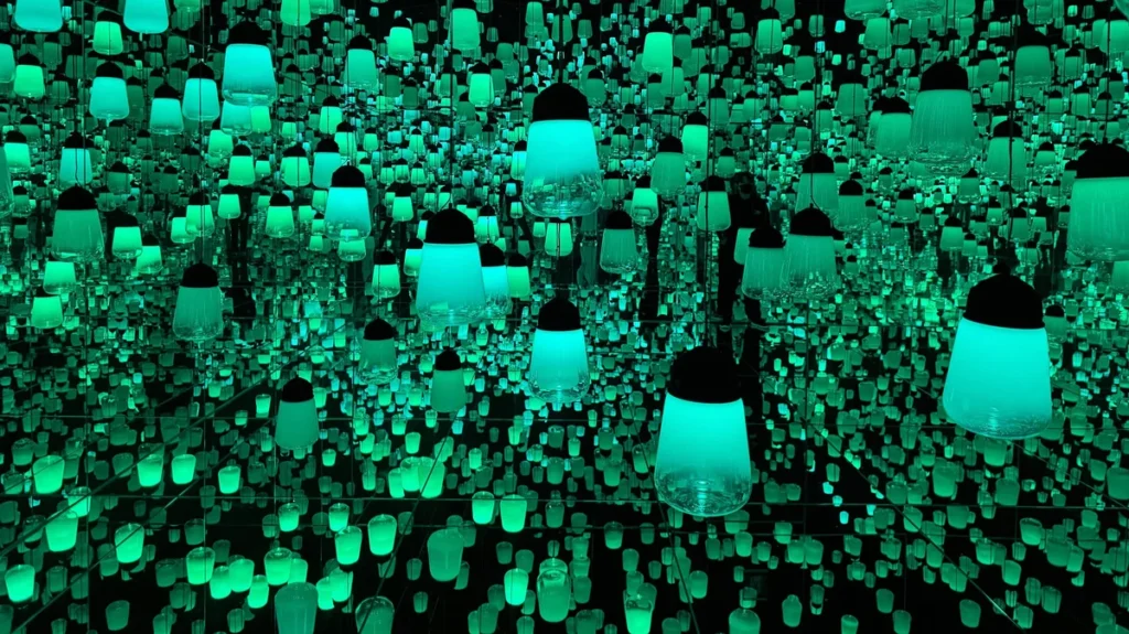 Glowing suspended light fixtures form a luminous wall inside teamLab Biovortex