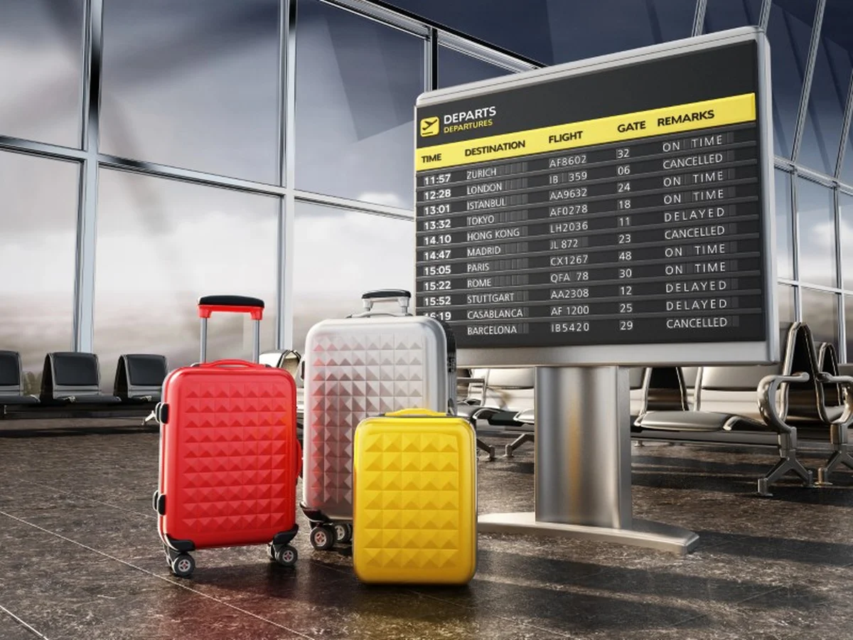 Colorful suitcases in front of a cancelled-flights departure board at an EU airport
