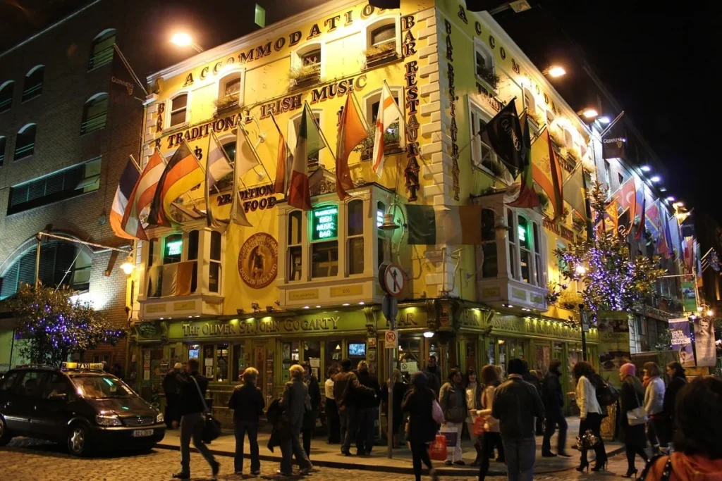 Lively Dublin street corner at night with warm lights and crowds outside a traditional Irish pub