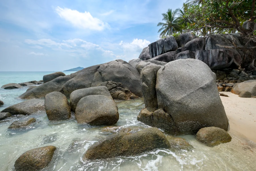 Granite boulders scattered on a white sand beach in turquoise water