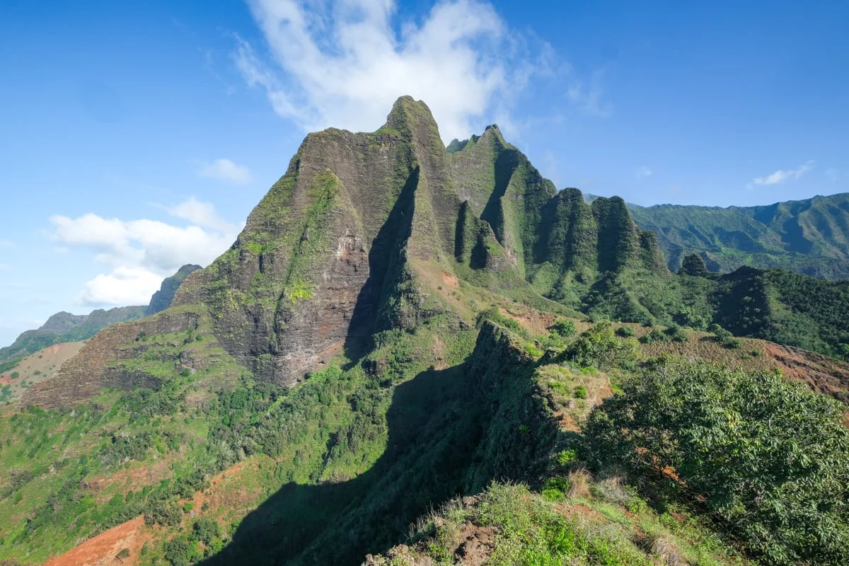 Steep green Na Pali mountain cliffs under a bright blue sky