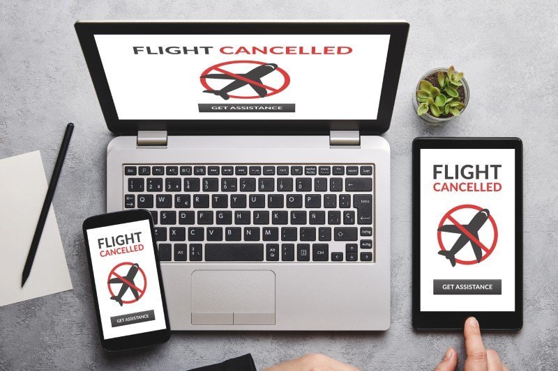 Laptop, tablet, and phone all displaying a flight cancelled notification